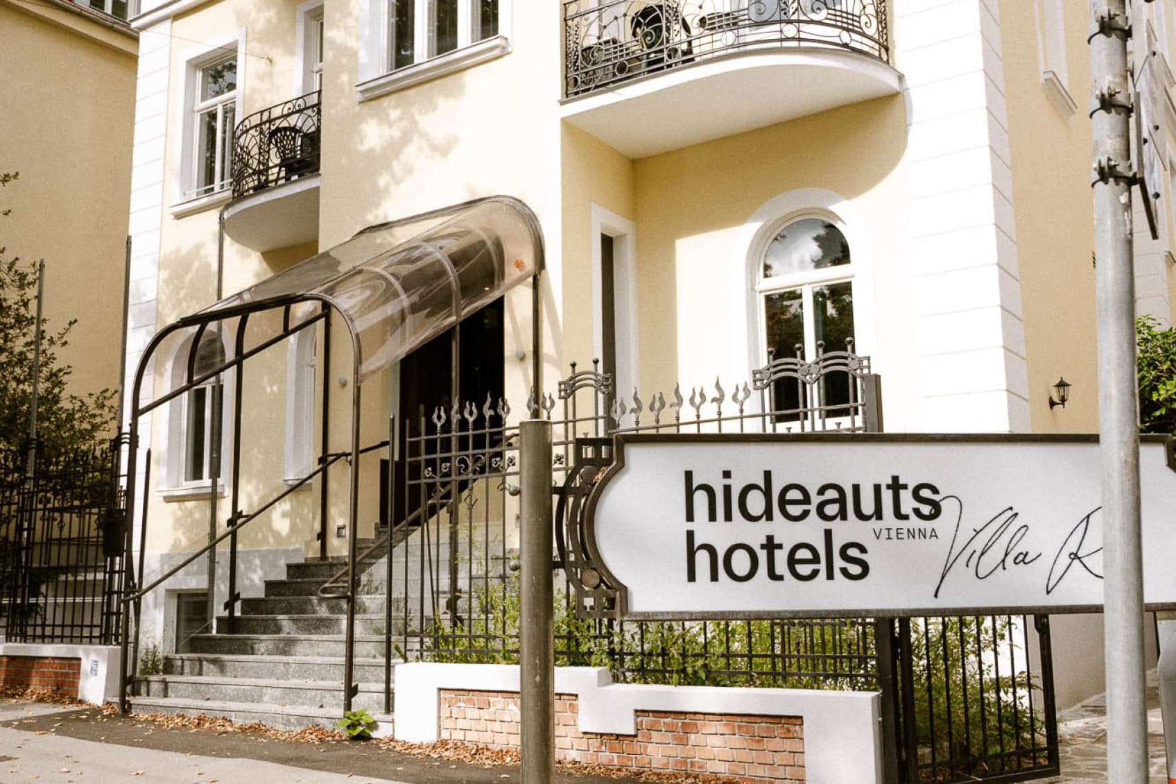 Seen is the hideuats hotels Villa r from the outside with the logo in front and the restored villa in the back.