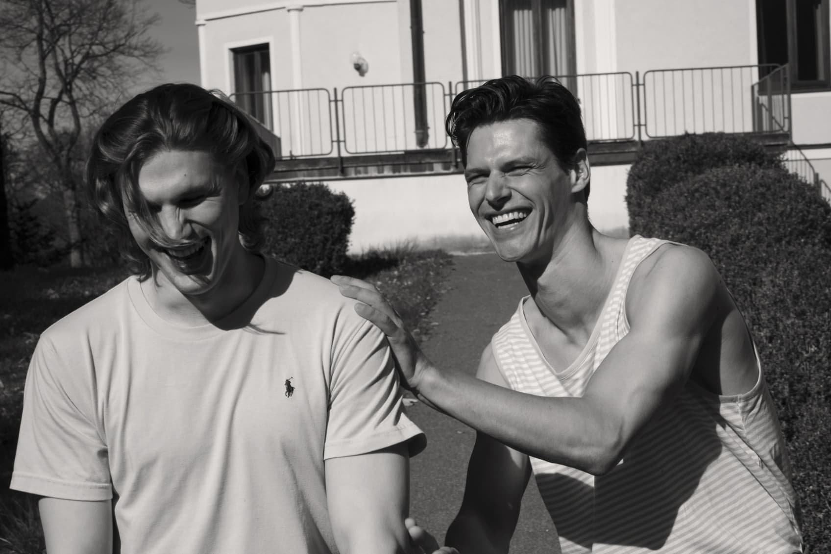 Two men walk laughing through the garden at hideauts hotels Der Rosengarten