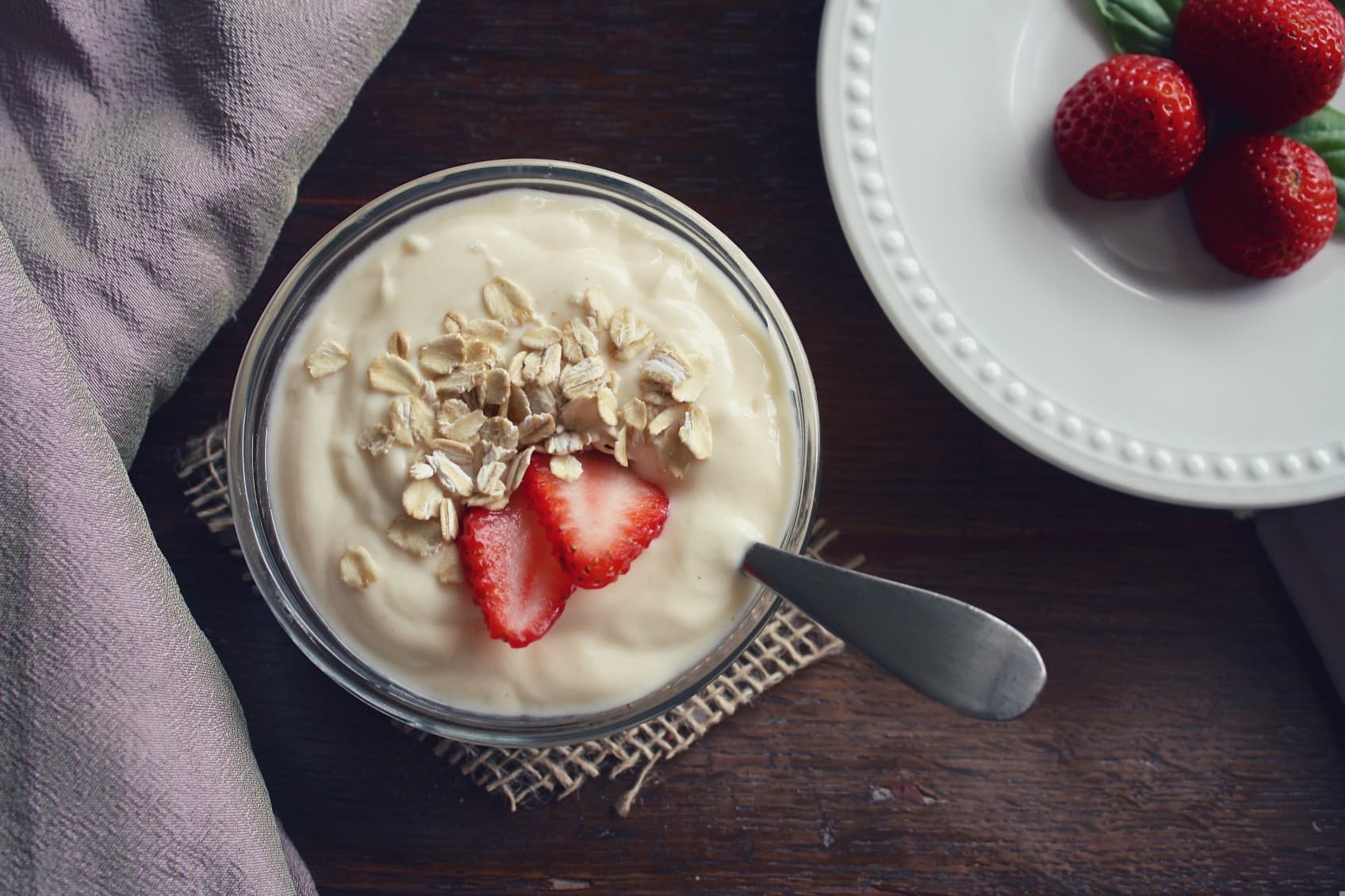 Yoghurt with berries and a spoon is in the yoghurt. Repesenting a possible breakfast choice at Villa R.