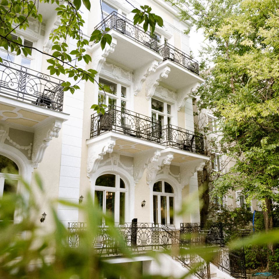 Seen is the ooutside of Villa R with a view onto the backside of the Villa and the balvonys. Shoot through the Garden.