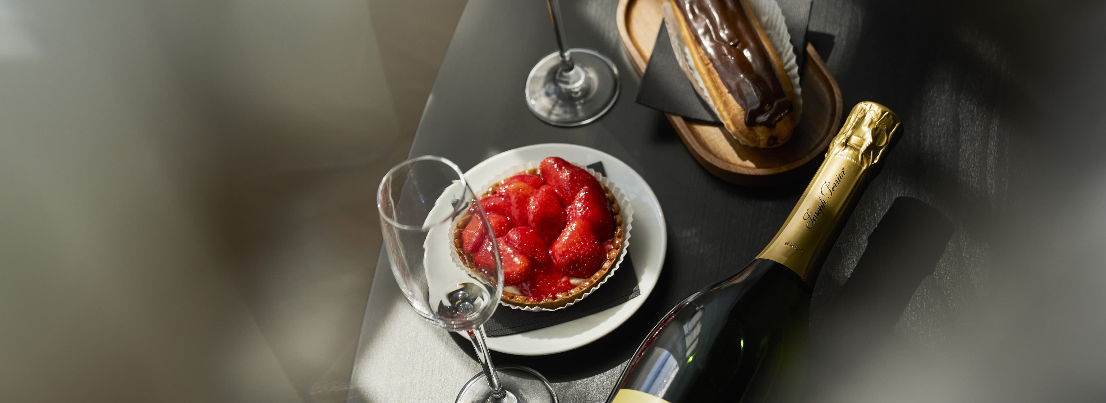 It shows a bottle of sparkling wine, with a piece of cake on a plate in the middle. Two glasses are also seen in the picture, making it the perfect cultural Vienna experience!
