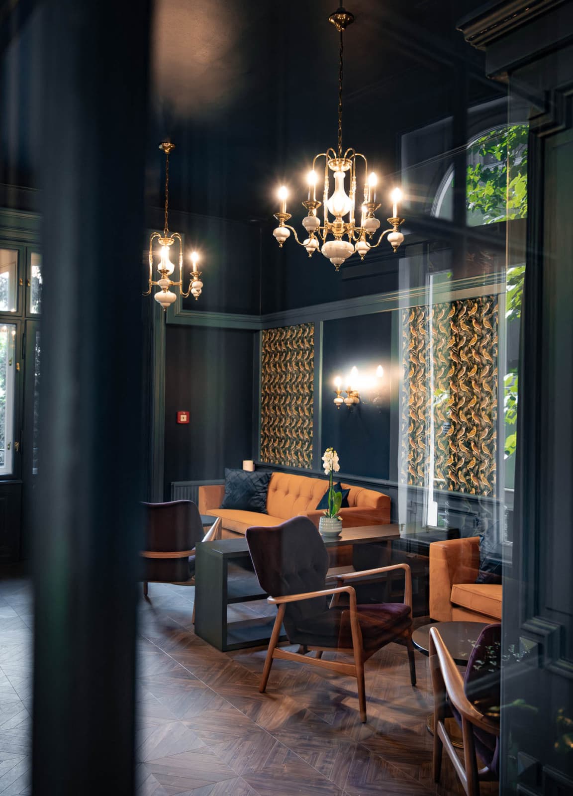 Seen is a wide shot of the lounge area, which is behind the lobby. It opens itself up to the garden and has been styled in a art deco style, which is complimented by the iconic and historic chandeliers.