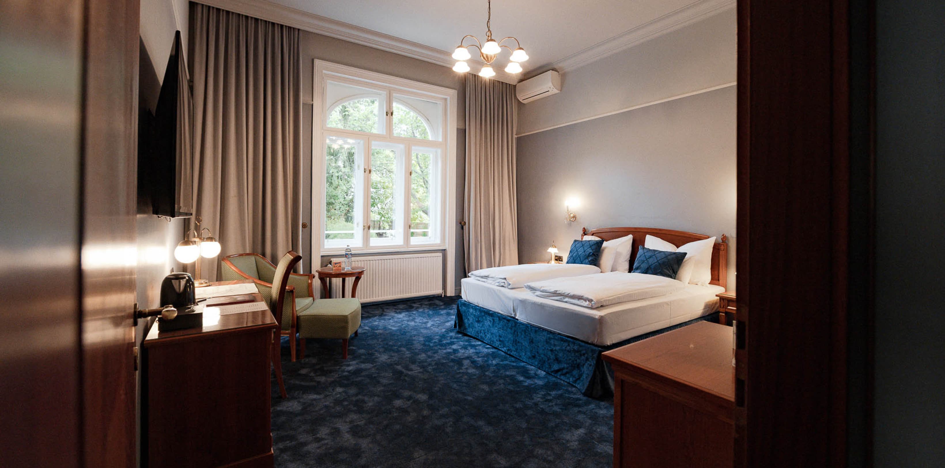 Pictured is a full view of the category Chic Garden View, which shows the double bed on the right hand side and the door to the balcony is straight ahead.