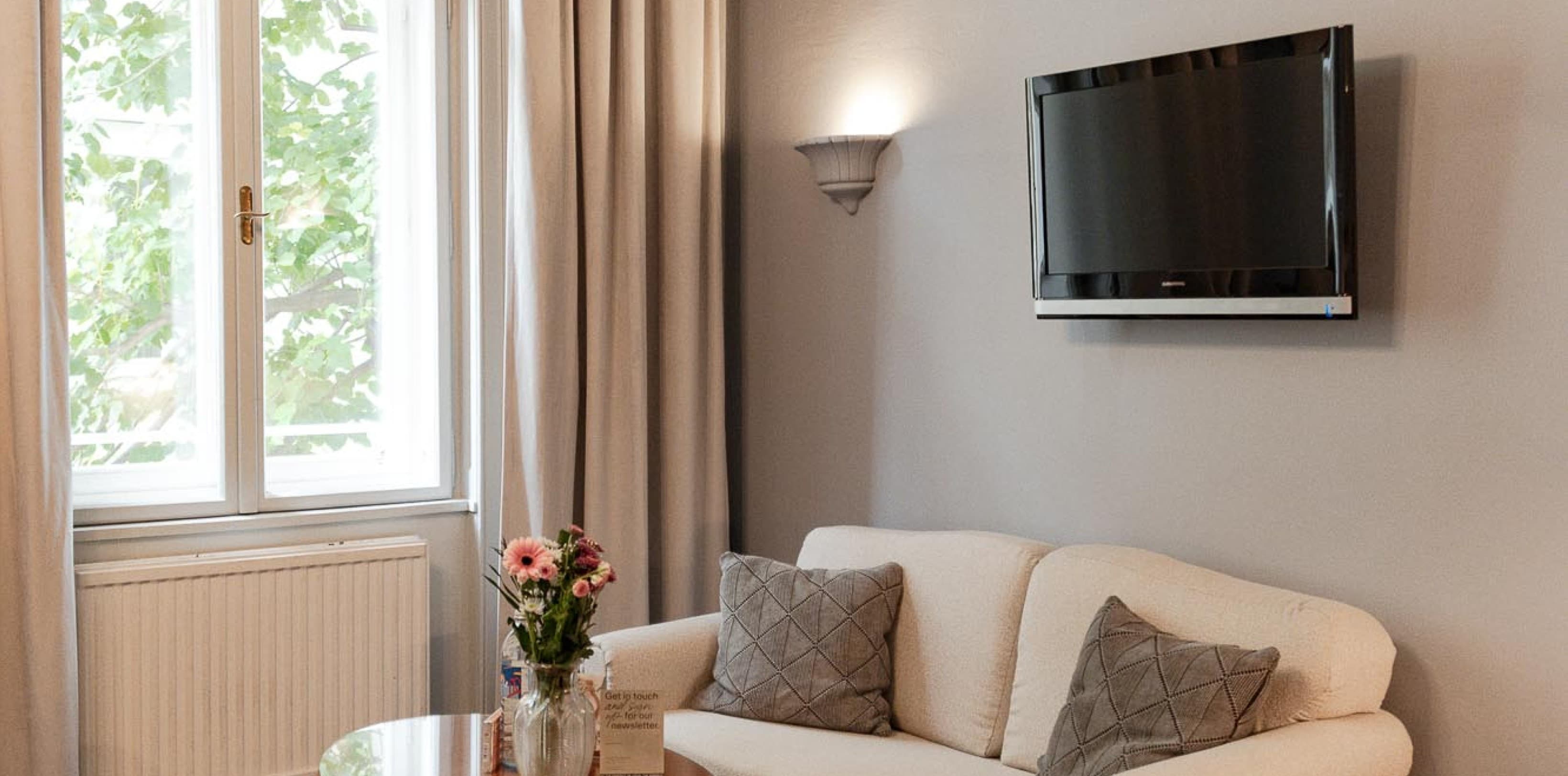 Seen is a wider shot of the leaving area of the room. Located opposite the bed, guests will find a couch as well as a desk to work at