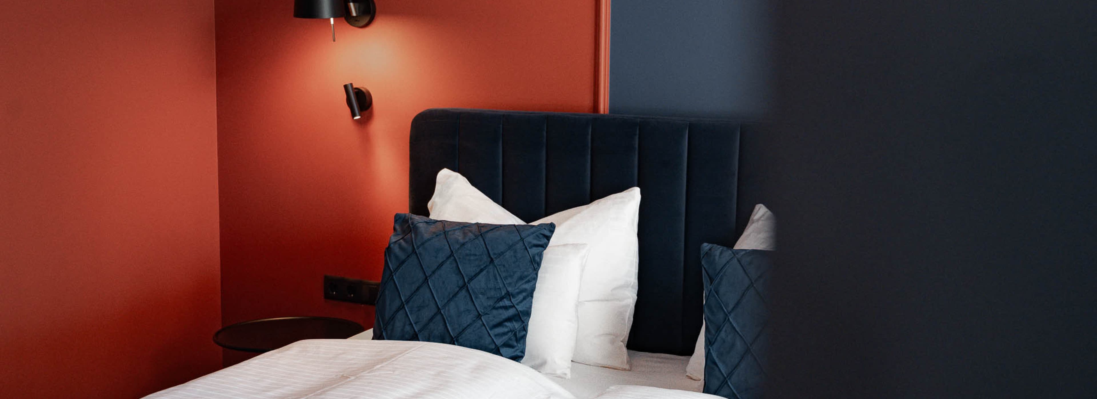 Zu sehen ist das Bett der Kategorie „Spacy“. Es handelt sich um ein Doppelbett mit dunkelblauen Details und einer orange-blauen Kombination auf der Rückseite.