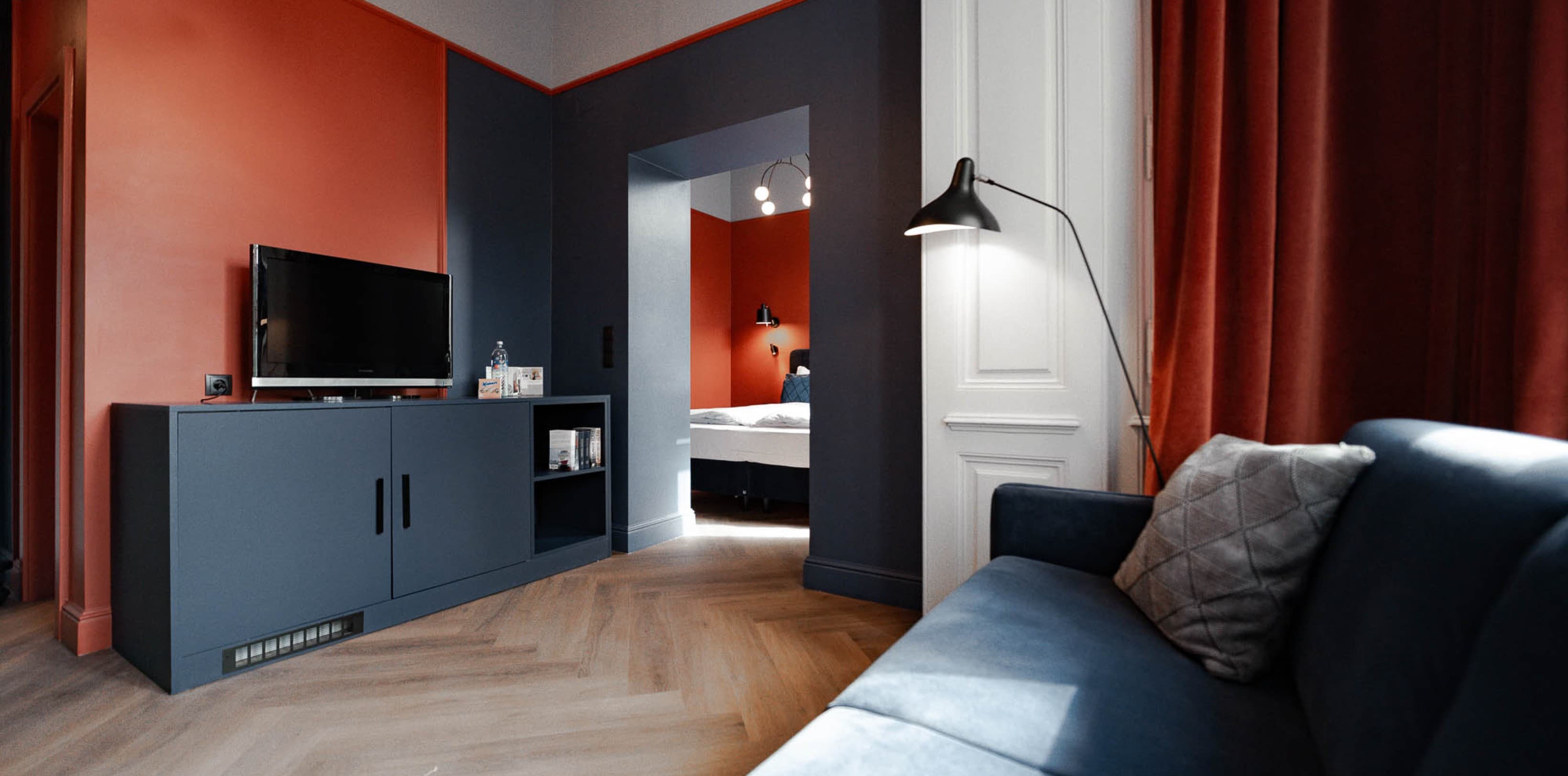Seen is the Spacy category and the view from the couch towards the bedroom. The biggest category offers a bedrooma as well as seperated living room. The colours Orange and Blue are also present here.