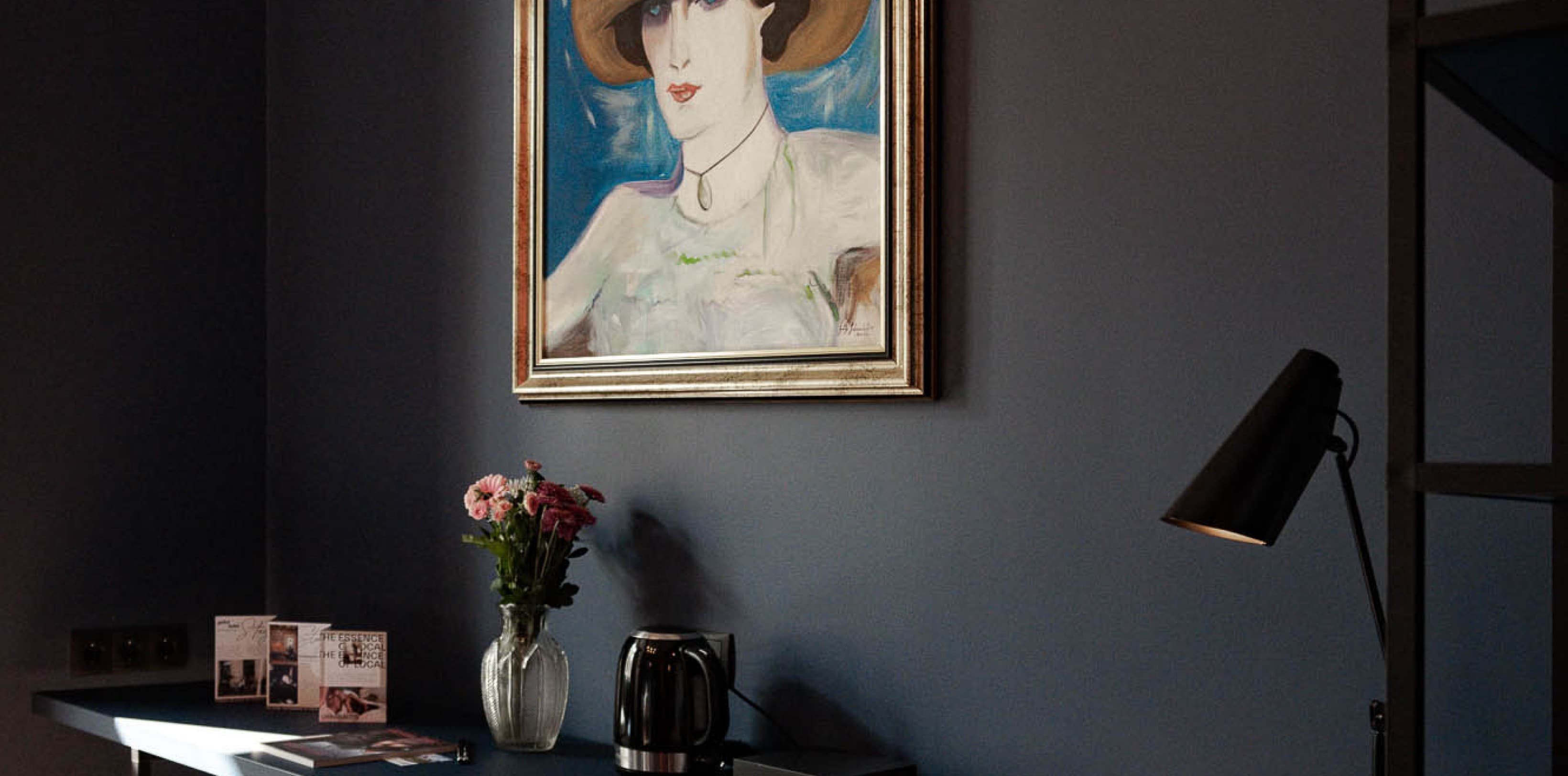 Part of the living area is a desk, that offers the opportunity to work at. The painting above it, shows a woman painted in a 20s style.