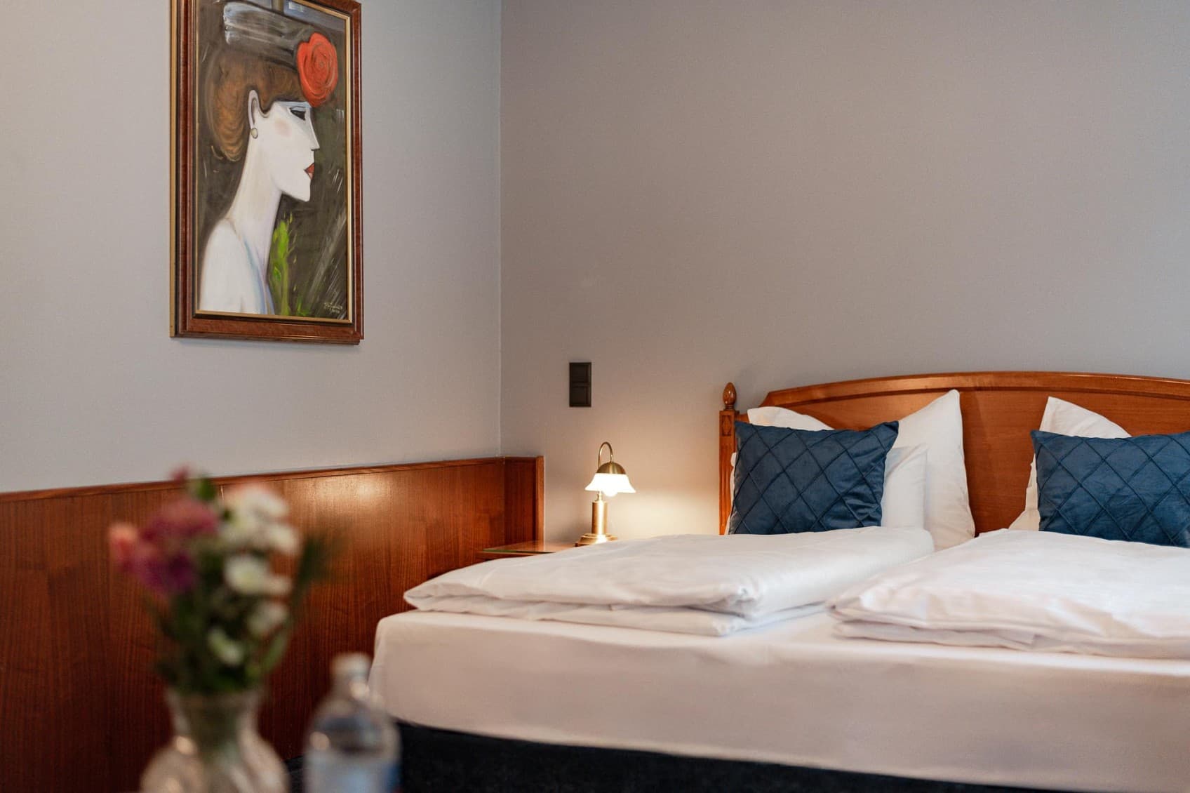 Seen is a possible Spacy bedroom, which shows a wooden bed on the right and piece of art of a woman on the left side.