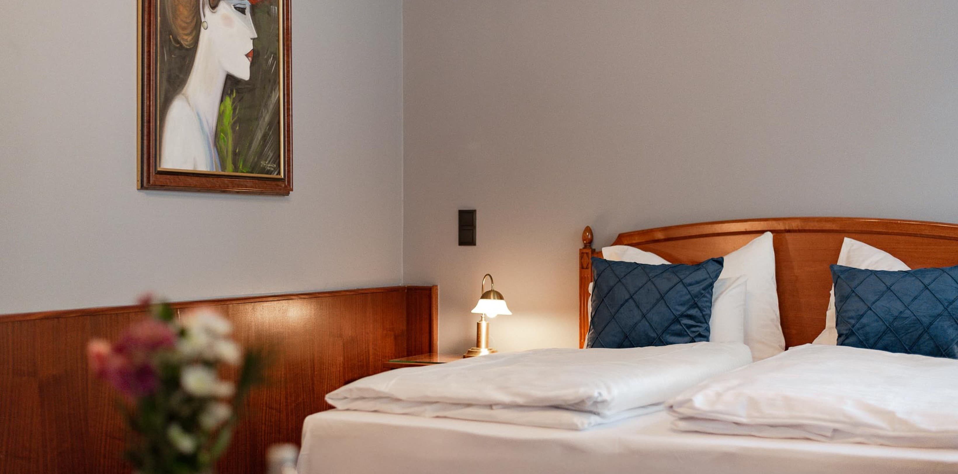 Seen is a possible Spacy bedroom, which shows a wooden bed on the right and piece of art of a woman on the left side.