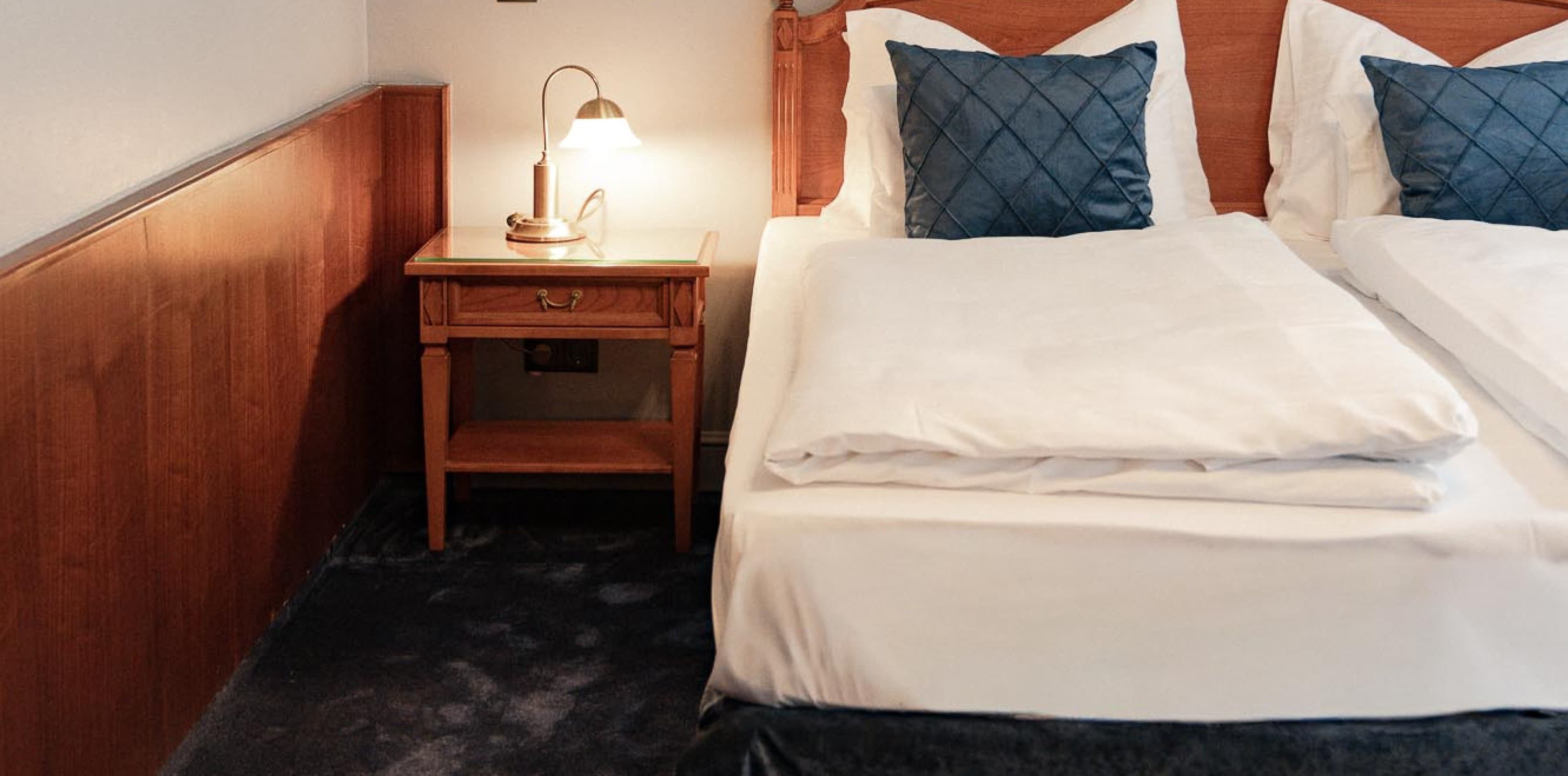 Seen is a possible picture of a Spacy Category, which shows the bed on the right side, a art piece hanging on the left side and a blue carpet.
